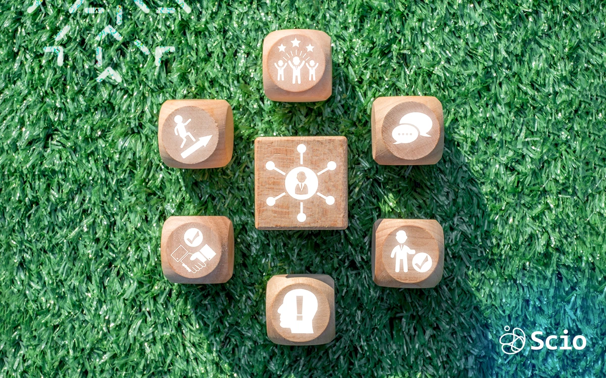 Wooden blocks with teamwork, communication, and leadership icons on green background