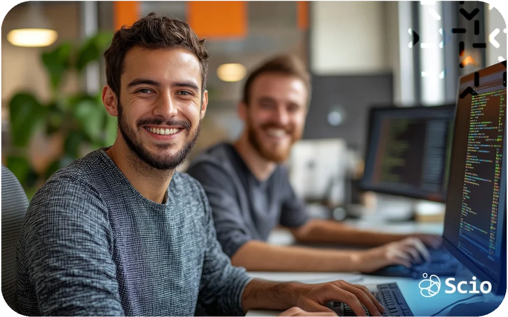 Two software developers working at computers reviewing code in a collaborative office environment