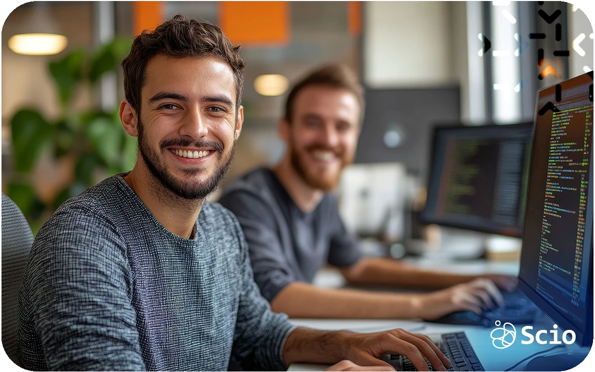 Two software developers working at computers reviewing code in a collaborative office environment
