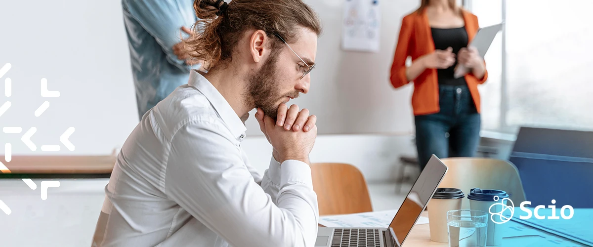 Software developer in a modern Texas office reflecting on collaboration anxiety during a team meeting
