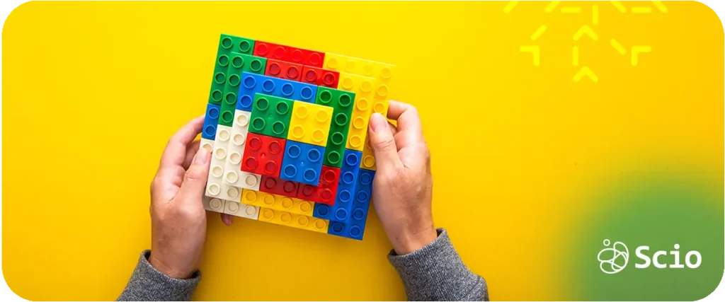 Hands assembling colorful LEGO bricks, demonstrating creativity guided by structural constraints.