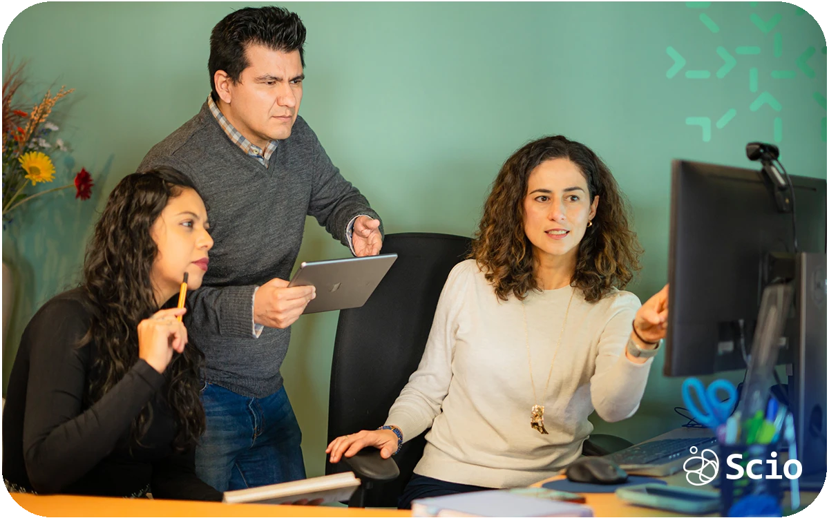 Software development team reviewing work together in front of a computer screen