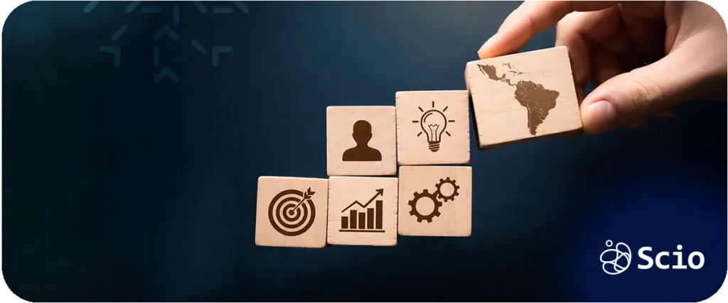 Hand placing a wooden block with a Latin America map icon on top of stacked business strategy blocks representing structured nearshore partnership growth.
