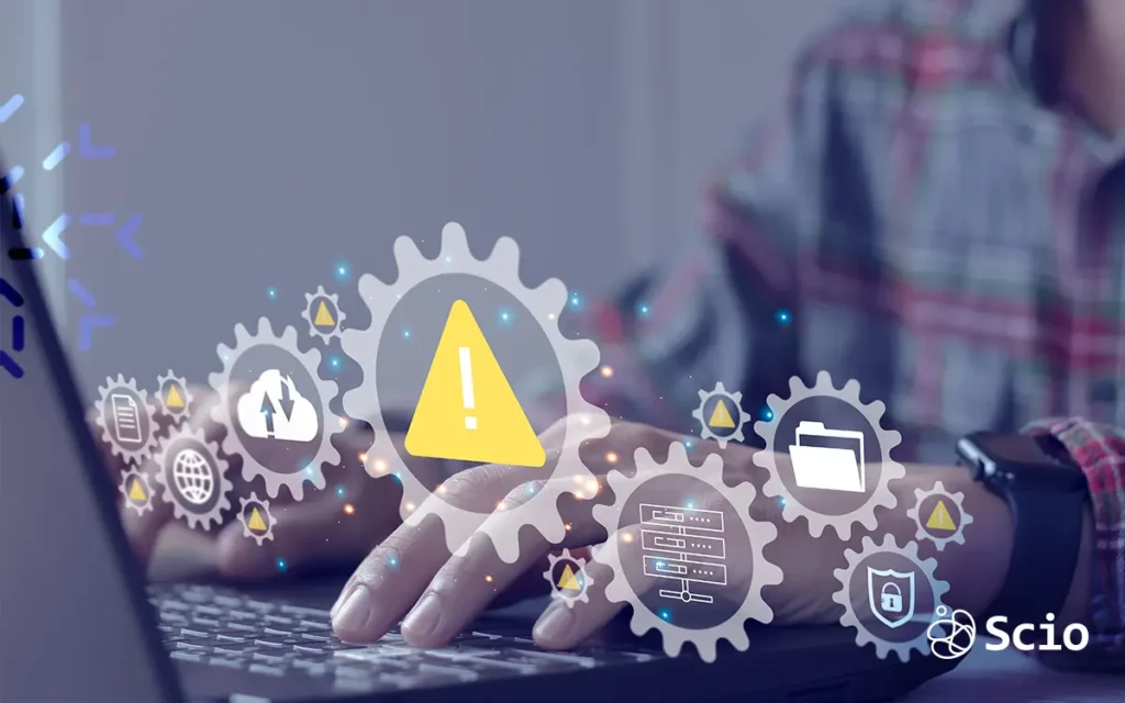Warning icon representing technical debt risks in legacy systems, shown over a developer's hands working on a laptop—Scio nearshore software development visual.