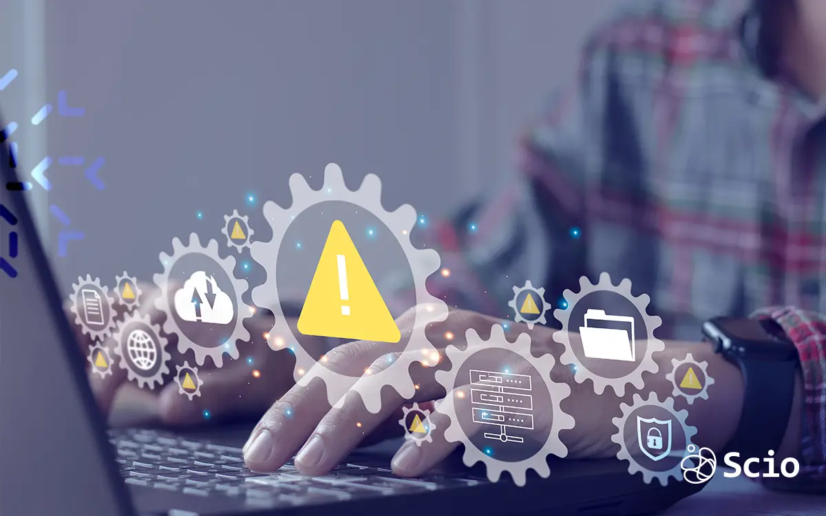 Warning icon representing technical debt risks in legacy systems, shown over a developer's hands working on a laptop—Scio nearshore software development visual.