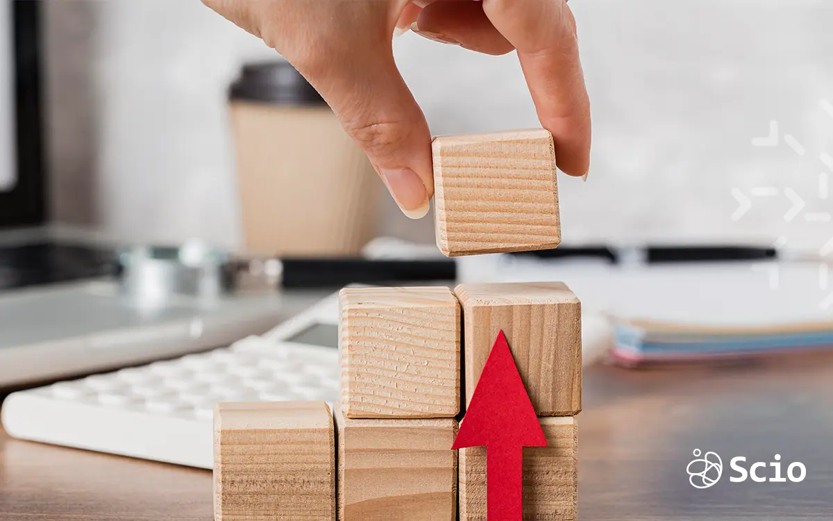 Hand stacking wooden blocks with an upward arrow, symbolizing continuous value delivery and incremental improvement in Agile software development.