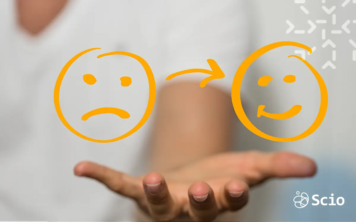 A hand holding a transition from a sad face to a happy face, symbolizing emotional recovery from burnout in dev teams.