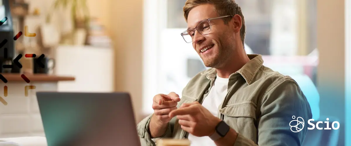 Smiling employee enjoying remote onboarding session at a coffee shop.