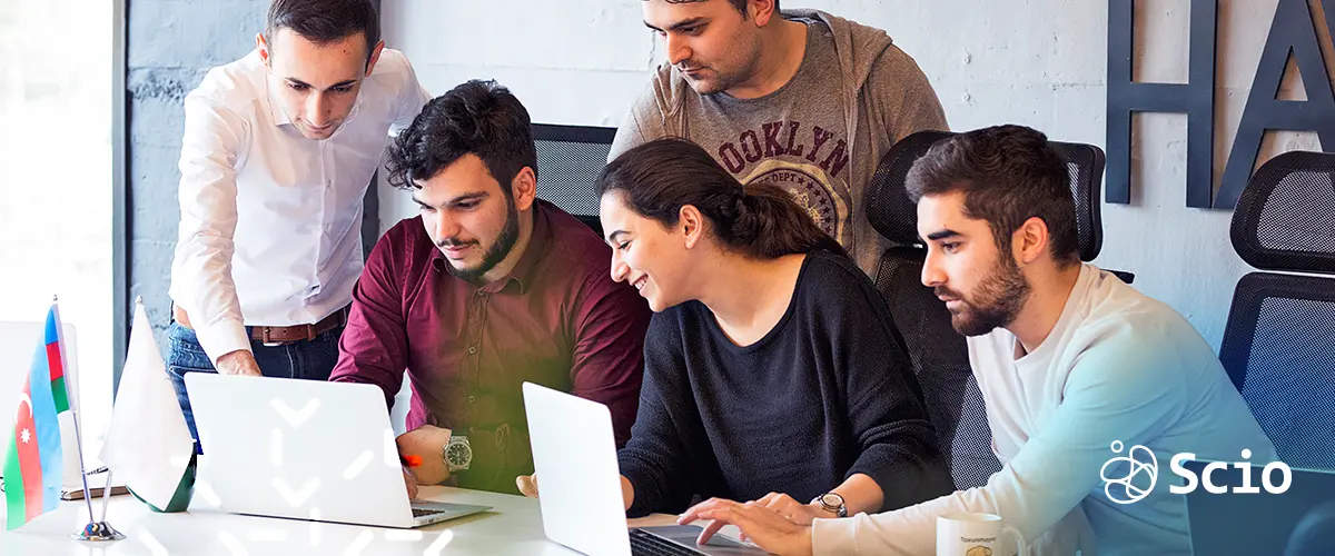 Agile development team collaborating around a laptop, illustrating teamwork and sustainable collaboration to prevent burnout.