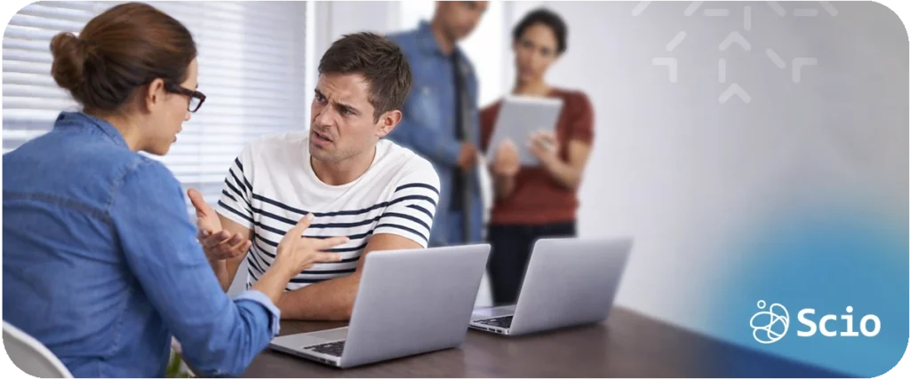 Conflict debt in teams: engineering team having a difficult conversation around laptops representing the tension caused by unresolved disagreement in a collaborative work environment