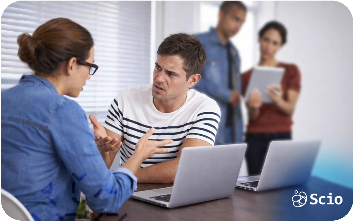 Engineering team having a difficult conversation around laptops, showing tension caused by unresolved conflict in a collaborative work environment.