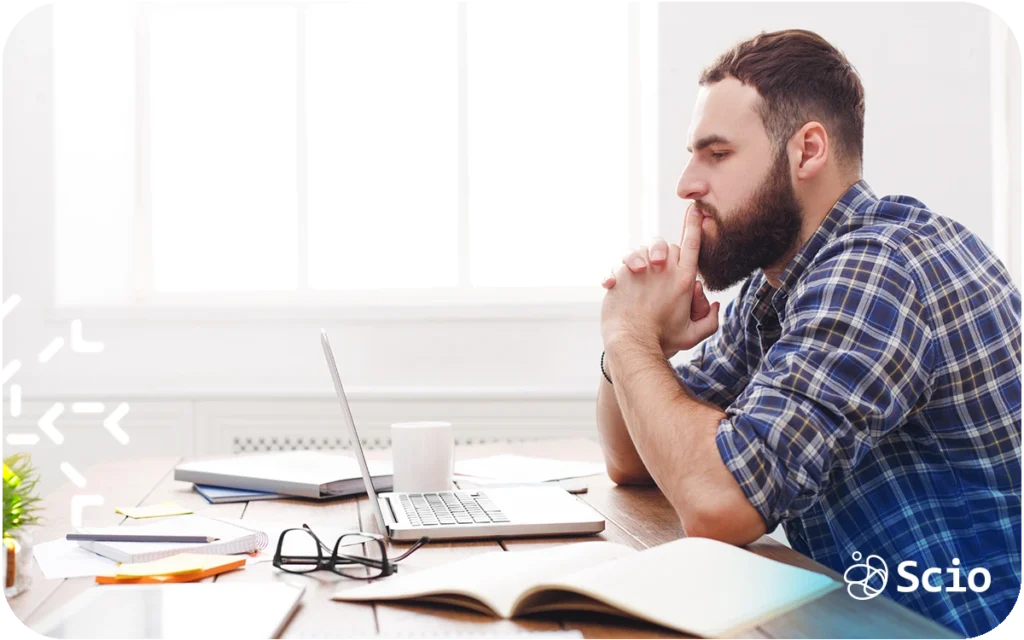 Engineering leader sitting at a desk looking thoughtful while working on a laptop, representing leadership overload and scaling pressure.