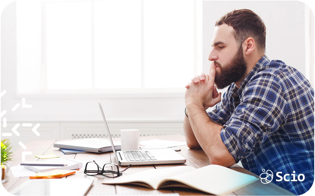 Engineering leader sitting at a desk looking thoughtful while working on a laptop, representing leadership overload and scaling pressure.
