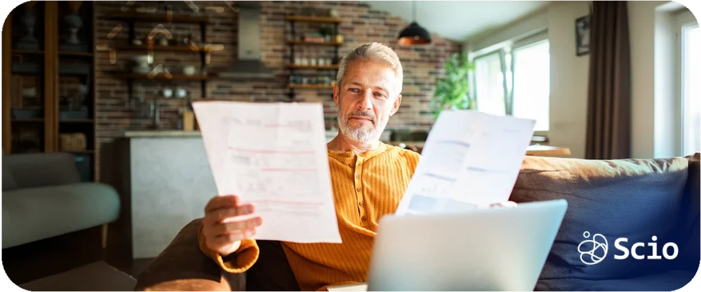 Senior professional reviewing financial documents on a laptop while evaluating the true cost of building an in-house software development team.