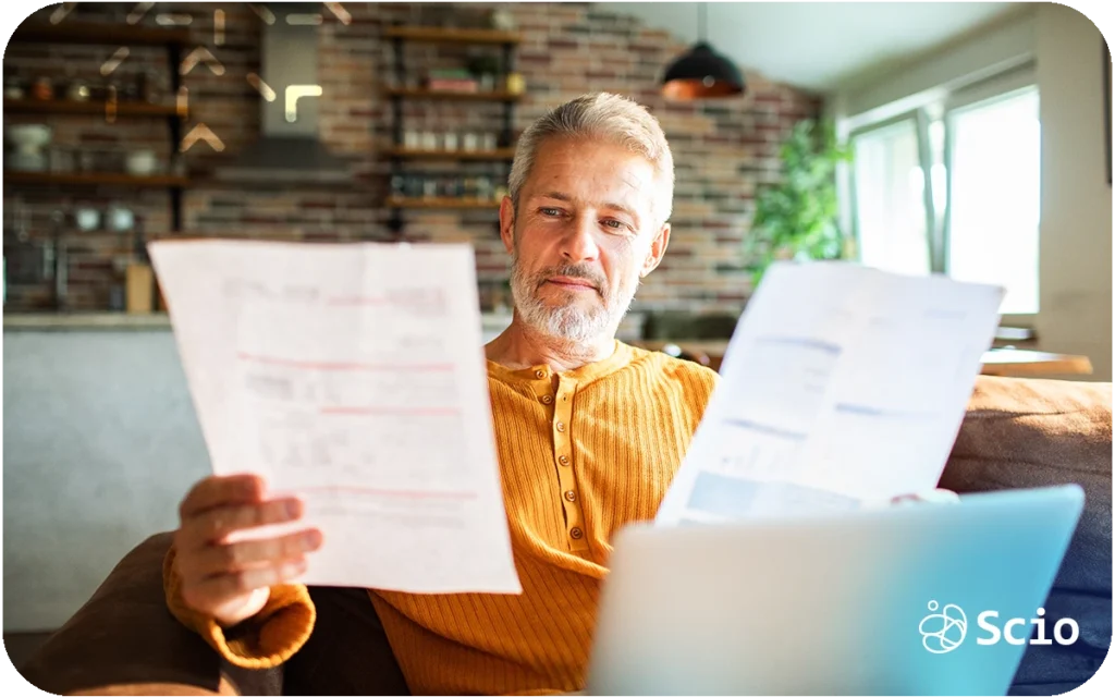 Senior professional reviewing financial documents on a laptop while evaluating the true cost of building an in-house software development team.
