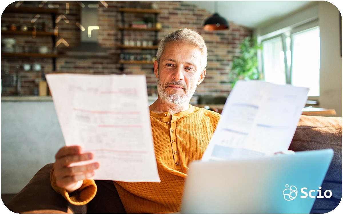 Senior professional reviewing financial documents on a laptop while evaluating the true cost of building an in-house software development team.
